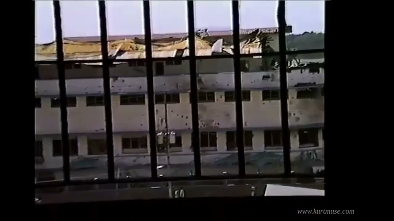View through prison window bars onto a shell-damaged building next to the prison