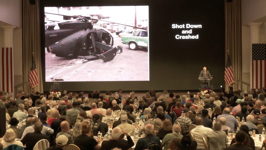 Kurt Muse speaking with helicopter backdrop